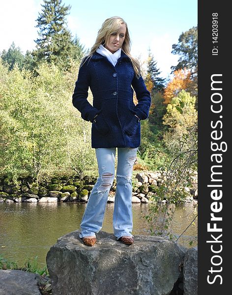 A lovely young woman standing on a rock by the Washougal river in Autumn