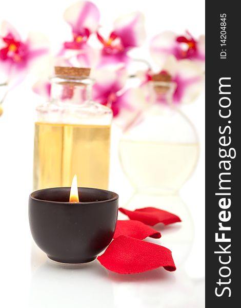 Body oils, rose petals and candle on white background. Body oils, rose petals and candle on white background