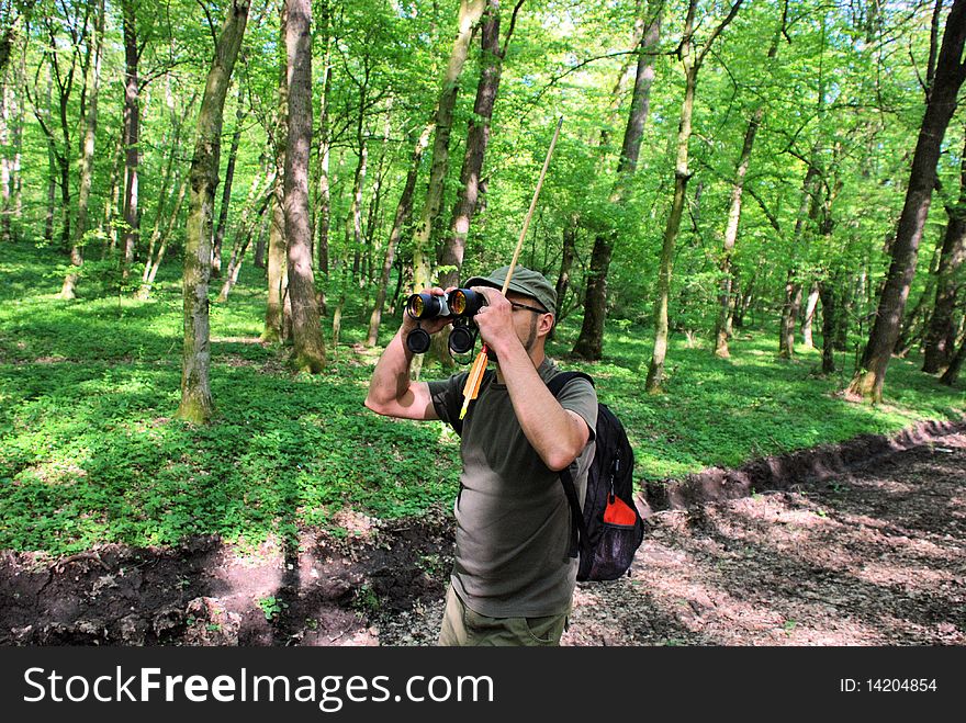 Man on the path with binocular exploring the forest. Man on the path with binocular exploring the forest
