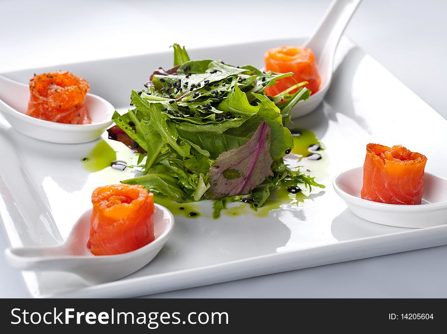 Salmon in a white plate. In the middle of rucola salad.