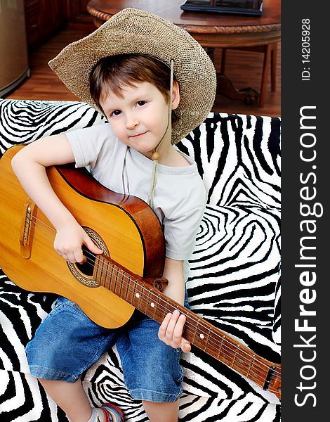 Shot of a little boy playing his guitar at home. Shot of a little boy playing his guitar at home.