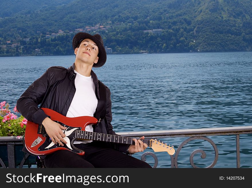 Young guitar player by the sitting at the Como lake in Italt