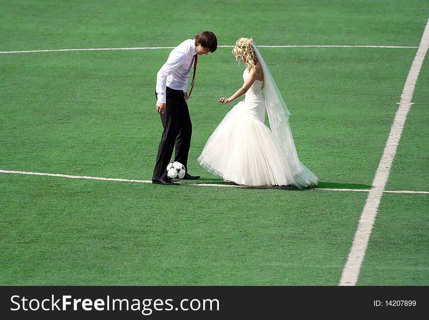 Young wedding couple playing football on the green field. Young wedding couple playing football on the green field