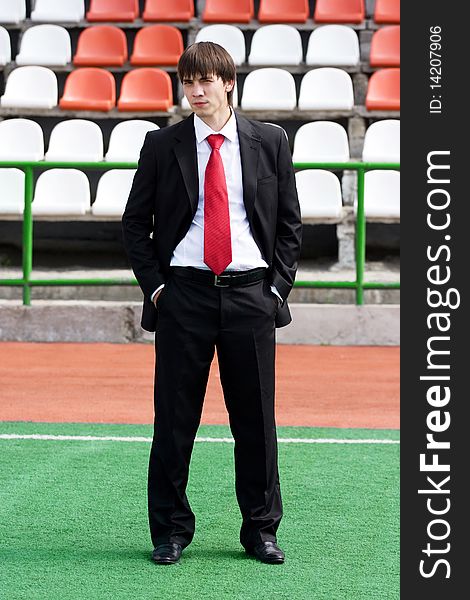 Young man in black suit standing near the audience bleachers. Young man in black suit standing near the audience bleachers