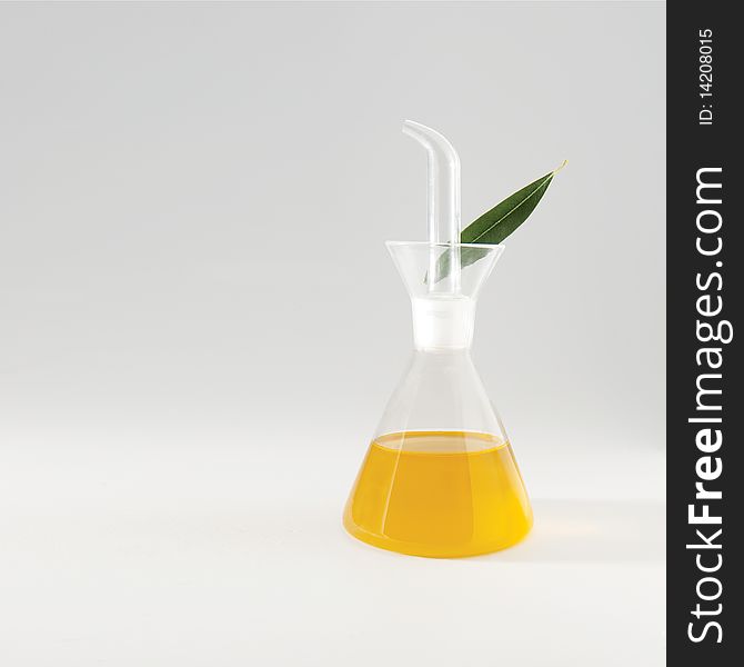 Olive oil in a glass can white an olive leaf