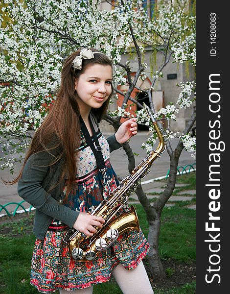 Beautiful smiling girl with saxophone, spring tree. Beautiful smiling girl with saxophone, spring tree