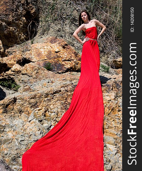 Woman in red dress from material and rocks