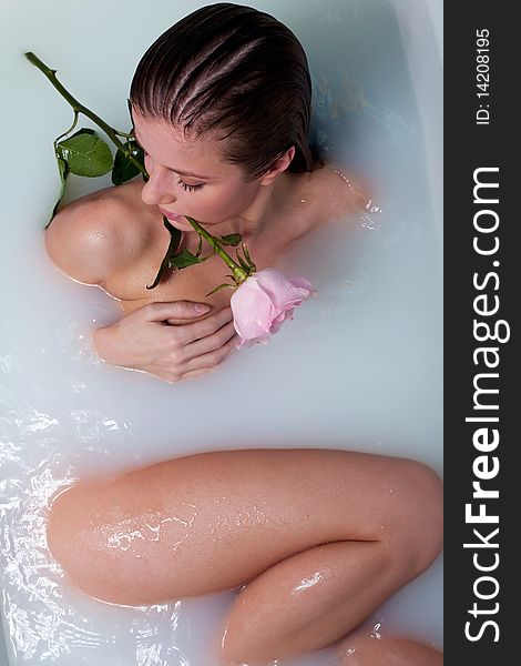 Beauty woman in bath with rose in milk water