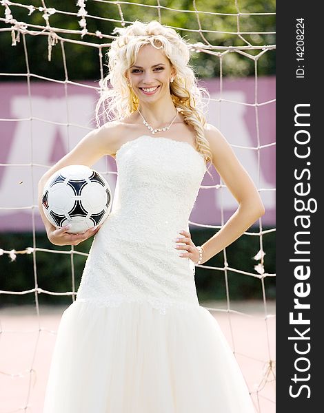 Young beautiful bride standing on the gate with ball. Young beautiful bride standing on the gate with ball