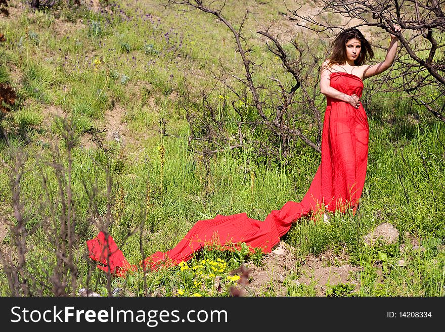 Young beautiful woman in red fabric in the forest