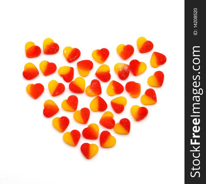 Large heart made from the small red and yellow fruit candies hearts on a white background. Symbol of sweet love. Large heart made from the small red and yellow fruit candies hearts on a white background. Symbol of sweet love.
