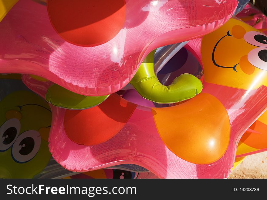 A stack of colorful children's float toys is stacked and waiting for a day of fun at the beach. A stack of colorful children's float toys is stacked and waiting for a day of fun at the beach.