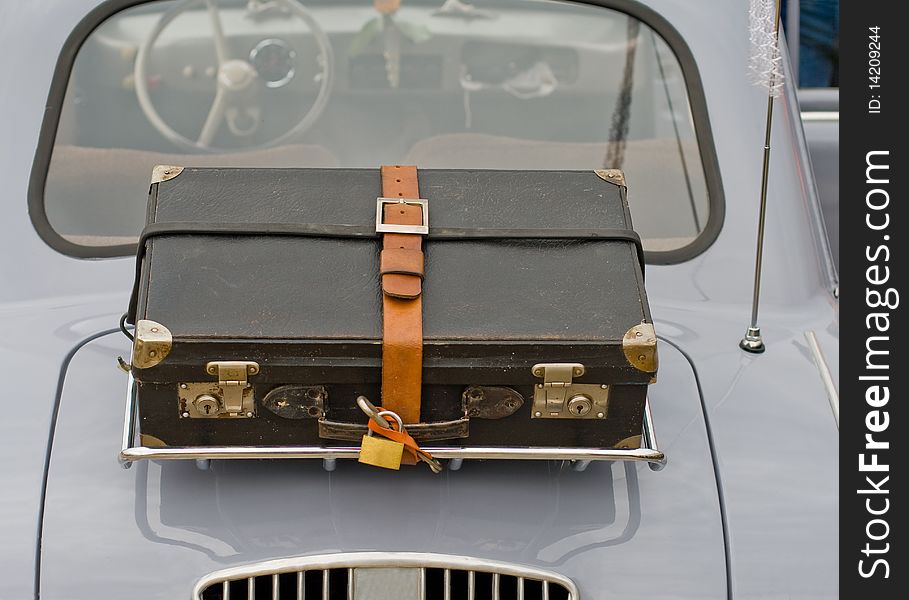 An old suitcase on the back of an old car. An old suitcase on the back of an old car