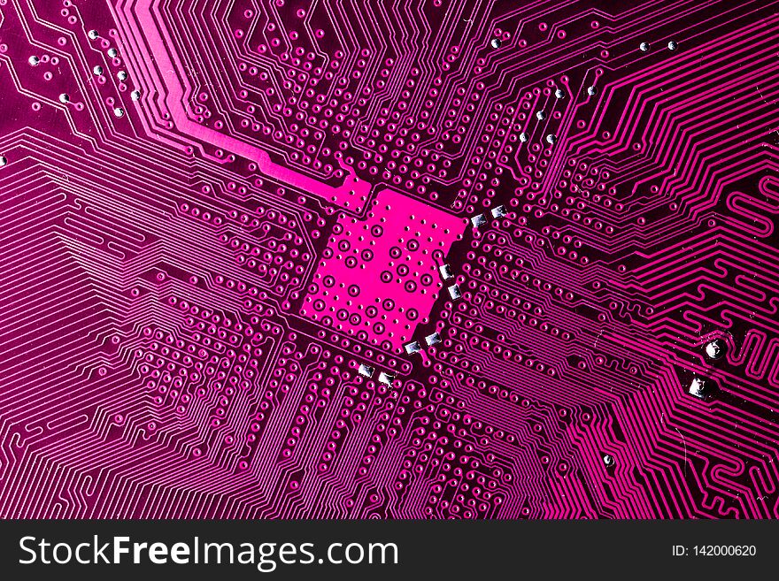 Close up photo of pink printecd circuit board with solder points. Close up photo of pink printecd circuit board with solder points