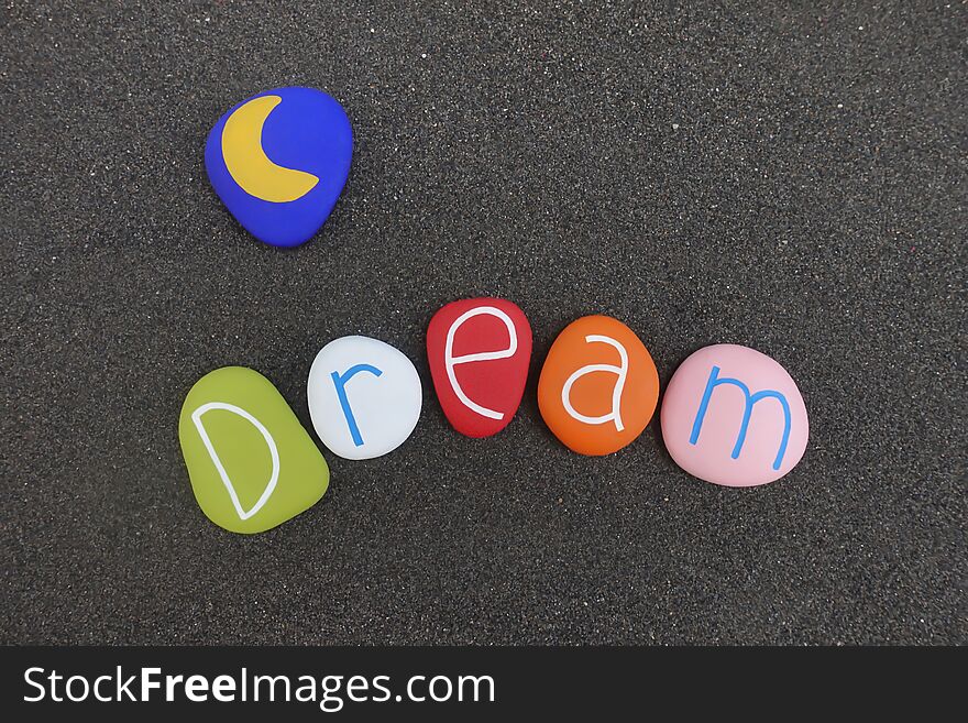 Dream text with multi colored sea stones over black volcanic sand