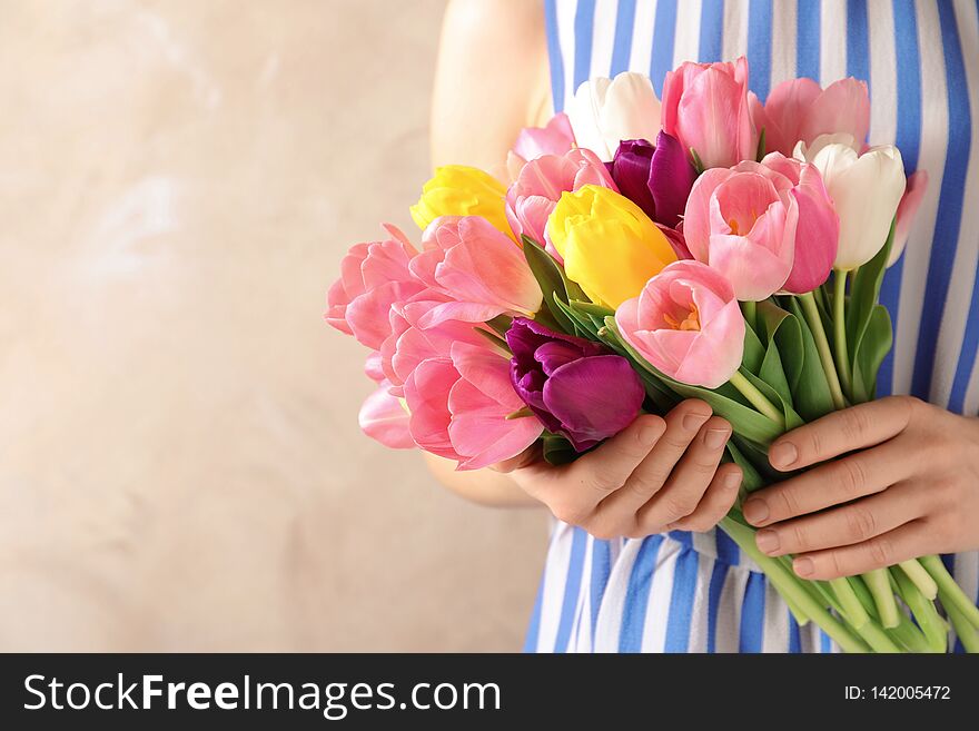Girl holding bouquet of beautiful spring tulips on color background, closeup with space for text. International Women`s Day
