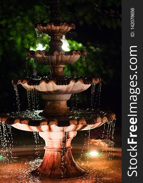 The fountain in a garden in the evening by the light of lamps. Romanticheskak atmosphere