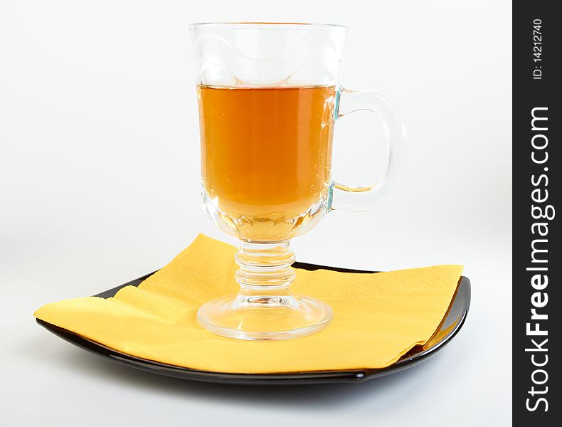 Сup of tea on black plate with yellow serviette on white background