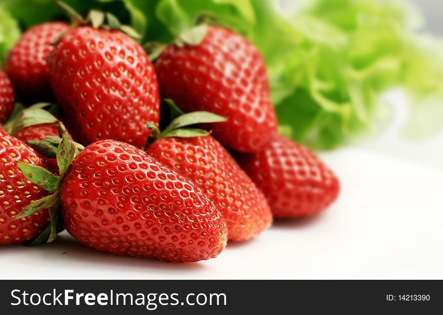 Juicy strawberries on white with green leaves on background