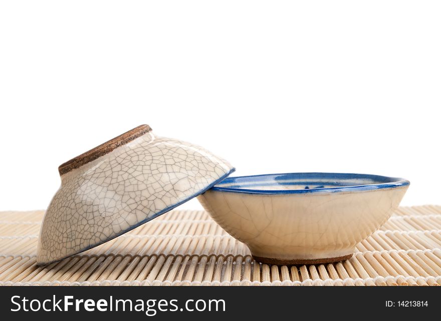 Two tea cups lie on mat isolated in white