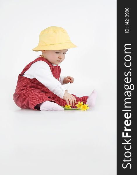 Sitting little girl in hat and with flower on white background.