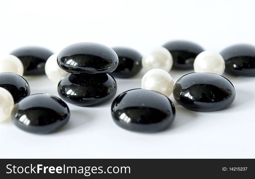 Black stones and white pearls on a white background