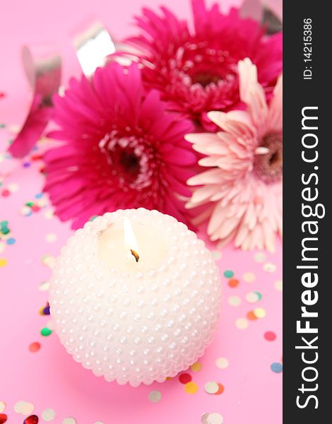 Flowers and candle on a pink background