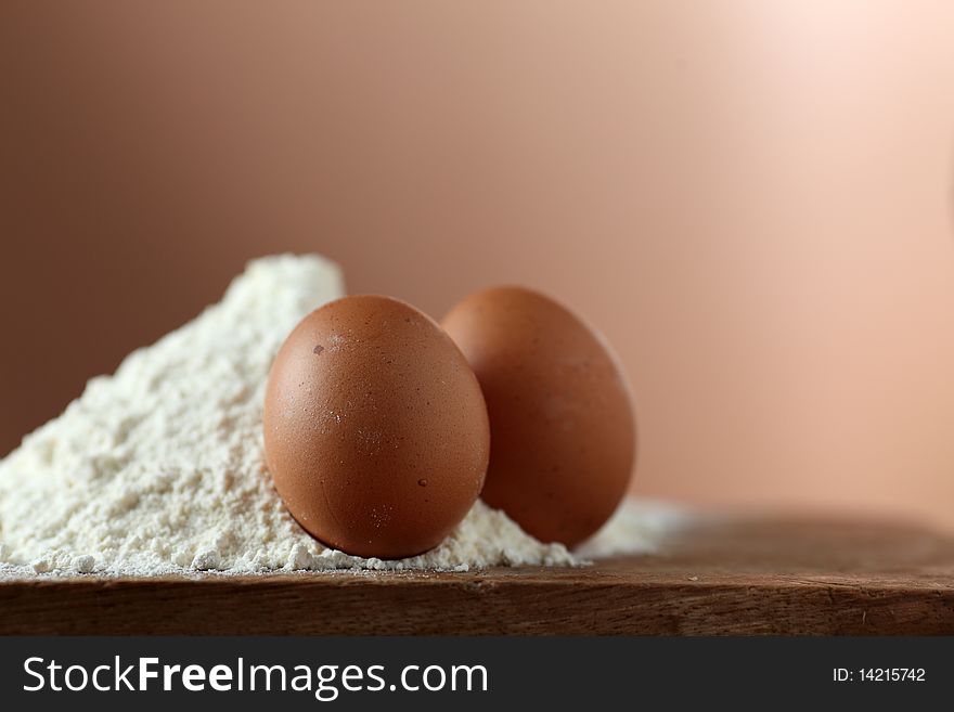 Two Eggs And Flour In A Kitchen On A Wooden Table