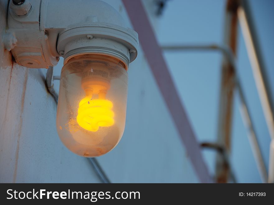 Yellow old-style retro light bulb on a dark evening