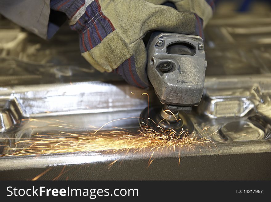 Man using a angle grinder on metal surface with sparks