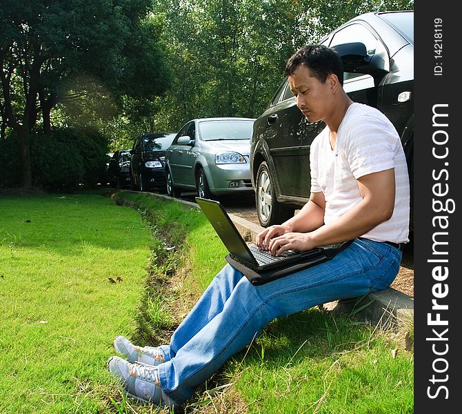Man using laptop aside the car outdoor.