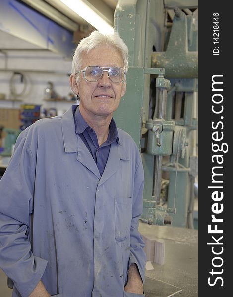 Portrait of senior worker on factory floor next to machine