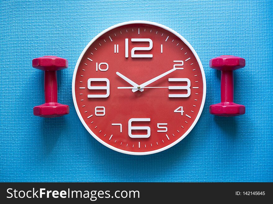 Time for exercising clock and dumbbell with yoga mat background, top view