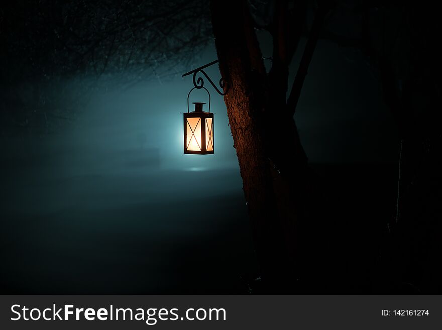 Beautiful colorful illuminated lamp in the garden in misty night. Retro style lantern at night outdoor