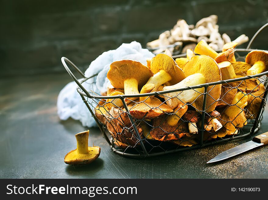 Raw mushrooms in basket and on a table