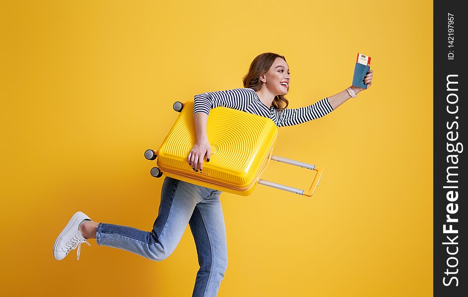 Go on an adventure! Happy woman going traveling. Young person with suitcase on color yellow background