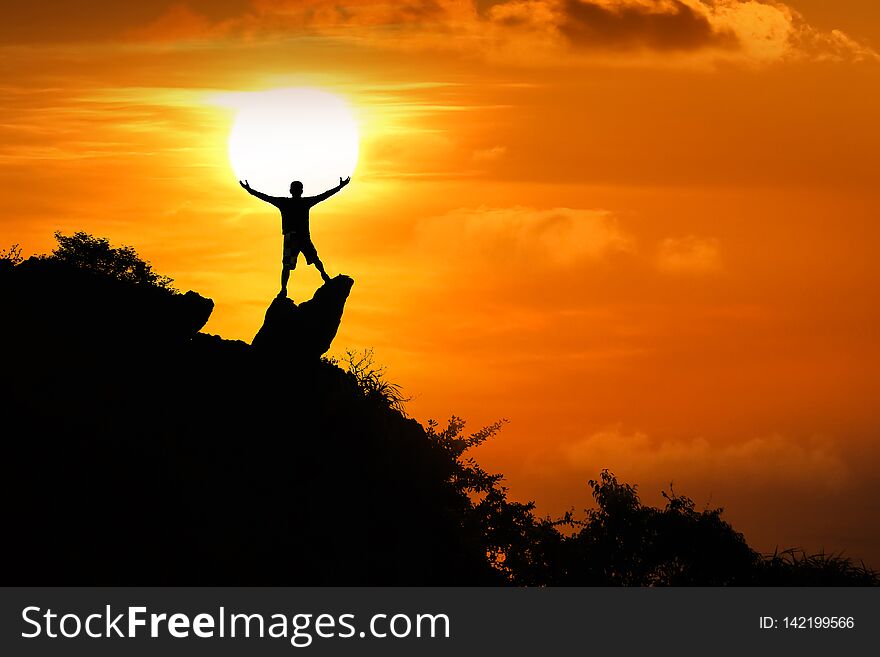 Man standing on the top of the mountain looking at red sky sunset background