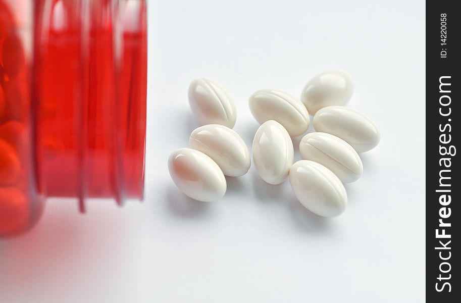 Close up of red vitamin bottle with white capsules. Close up of red vitamin bottle with white capsules