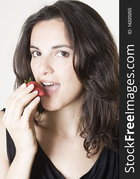 Young woman eating red strawberry
