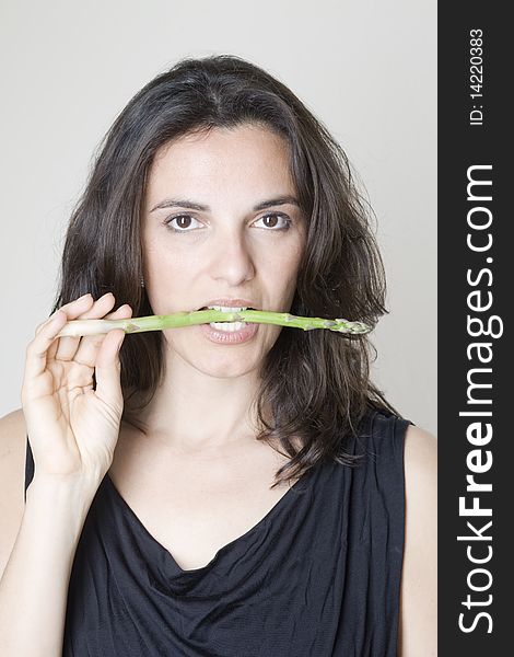 Woman biting a green asparagus. Woman biting a green asparagus