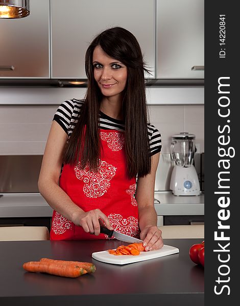 Pretty girl cooking and cutting carrot in the kitchen. Pretty girl cooking and cutting carrot in the kitchen.