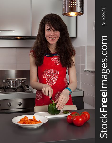 Pretty girl cooking and cutting green pepper in the kitchen. Pretty girl cooking and cutting green pepper in the kitchen.