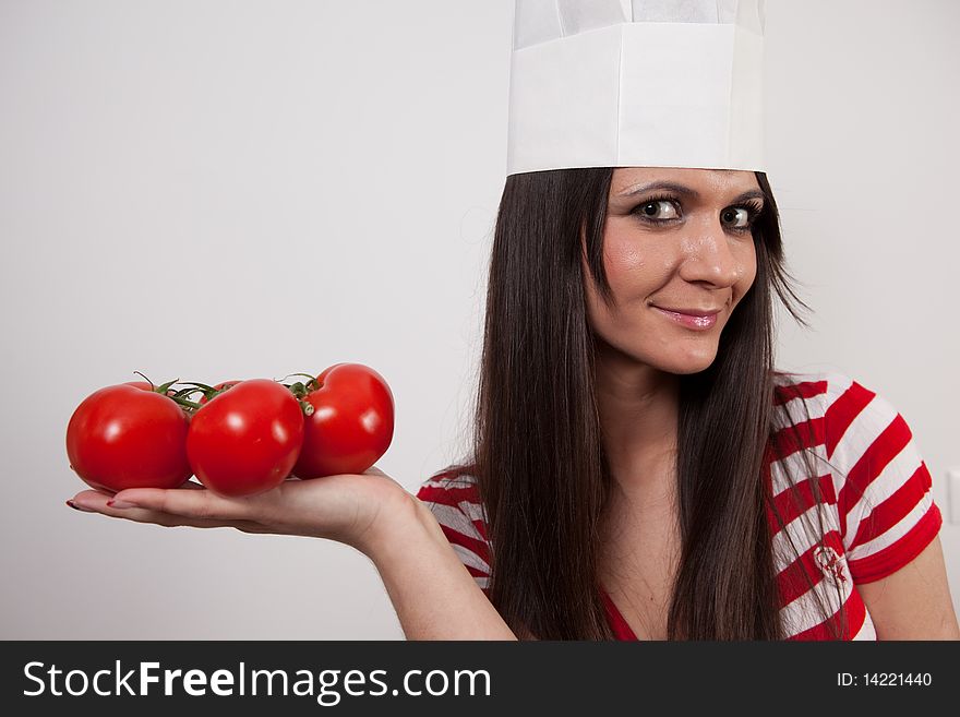 Cloes-up of a lovely  girl wearing cook cap and holding tomatoes, isolated on white. Cloes-up of a lovely  girl wearing cook cap and holding tomatoes, isolated on white.