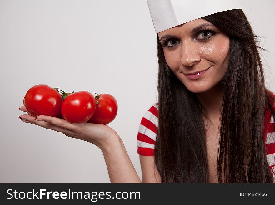 Cloes-up of a lovely  girl wearing cook cap and holding tomatoes, isolated on white. Cloes-up of a lovely  girl wearing cook cap and holding tomatoes, isolated on white.