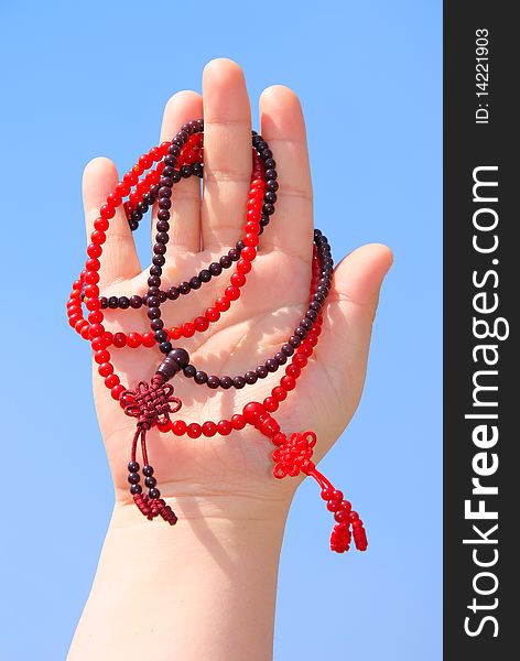 Prayer beads in her hands.Against the background of blue sky.