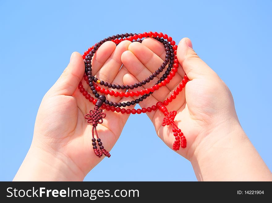 Prayer beads in her hands.Against the background of blue sky.
