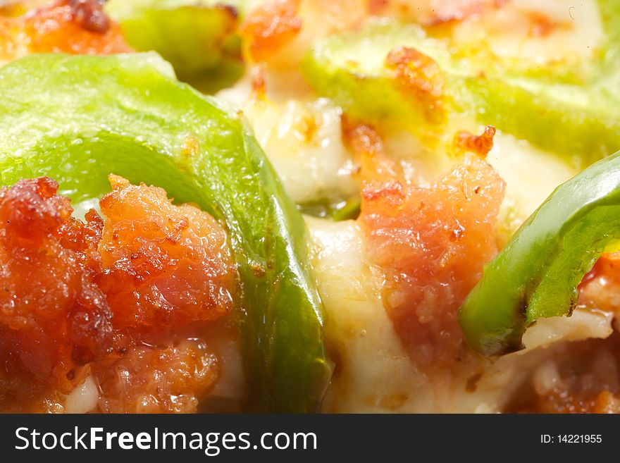 An extreme close up of pizza toppings on a slice, including meat, cheese and green peppers. An extreme close up of pizza toppings on a slice, including meat, cheese and green peppers