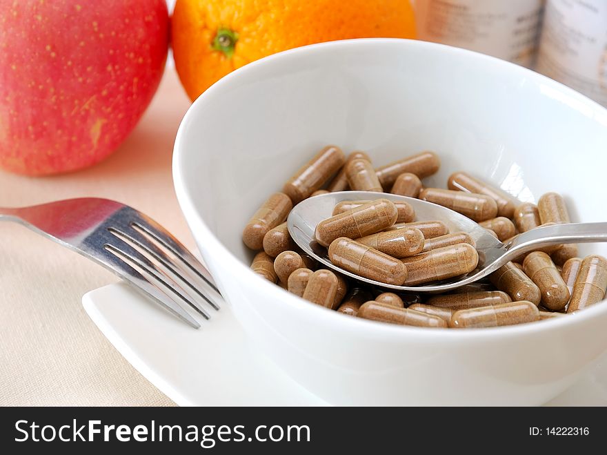 Spoonful of medicine capsules in soup bowl with fruits in background. Signifying drug addiction, healthy eating and lifestyle, dieting and slimming, and healthcare concepts. Spoonful of medicine capsules in soup bowl with fruits in background. Signifying drug addiction, healthy eating and lifestyle, dieting and slimming, and healthcare concepts.