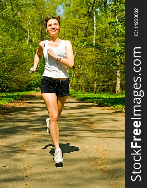 Smiling young woman running in park. Smiling young woman running in park