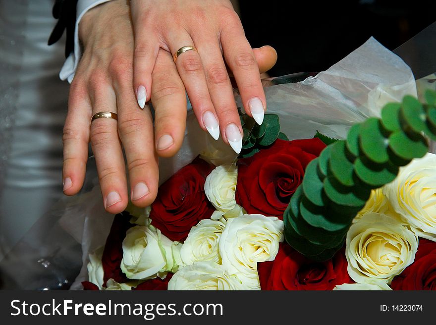 Hands with wedding rings and fowers bouquet